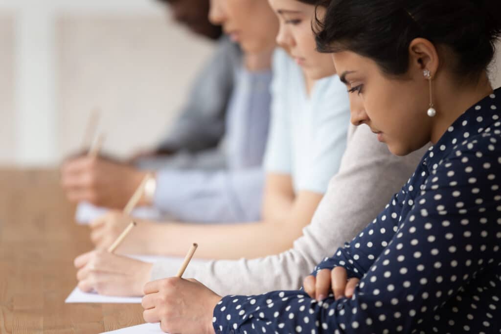 Students looking at papers and holding pens