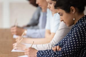 Students looking at papers and holding pens